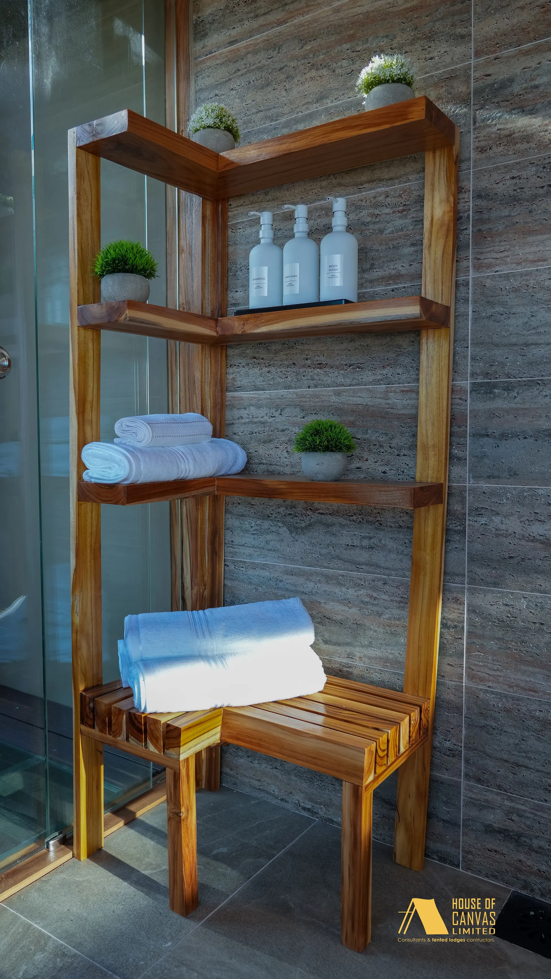 Handmade teak shelving stacked with towels and amenities at Kili Fair 2026